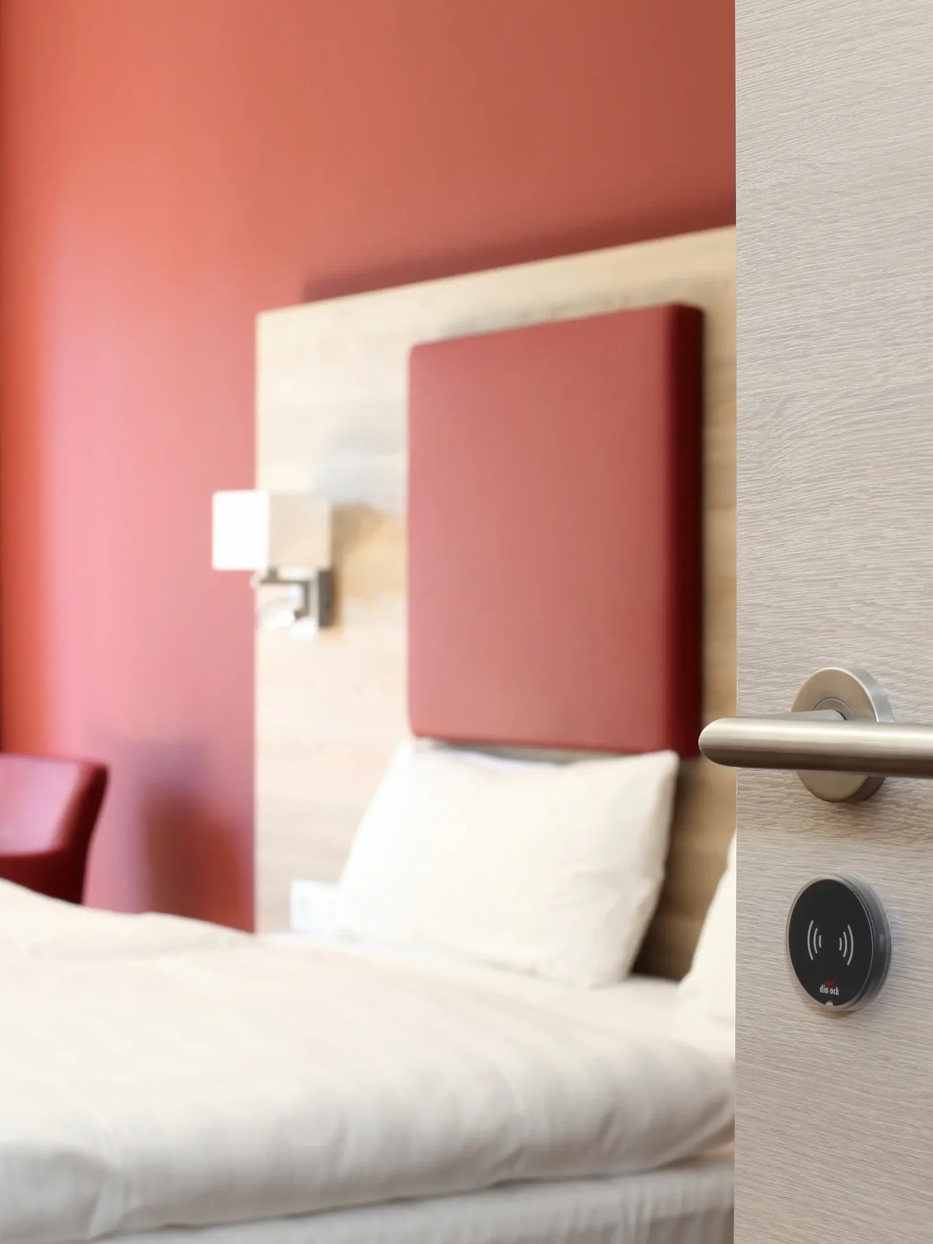 Close-up of a door handle with a bed in the background